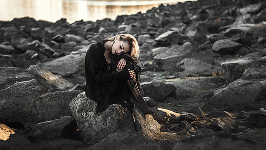 woman wearing black suit sitting on the gray rock thumbnail