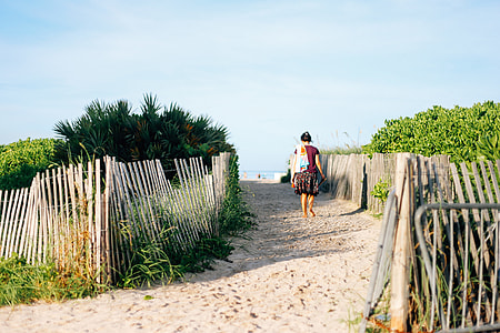 woman walking on sand between wooden fences thumbnail