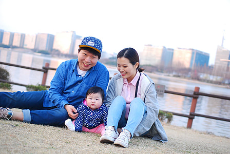 baby sitting between man and woman during daytime thumbnail