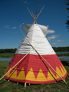 white, red, and yellow tipi tent on grass field thumbnail