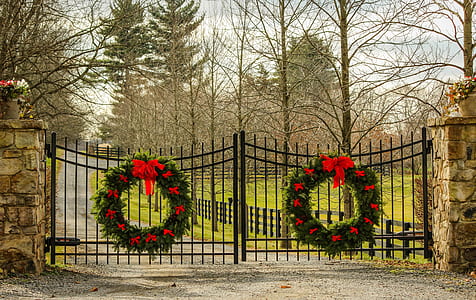 two large Christmas wreaths hanging on metal double gate thumbnail