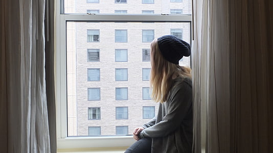woman wearing knit hat sitting on window thumbnail