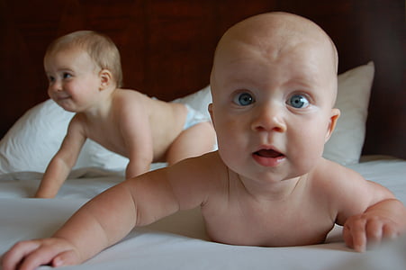 two babies laying on bed in room thumbnail