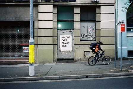 person riding on bike beside street thumbnail