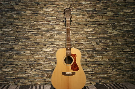 brown acoustic guitar leaning on wall thumbnail