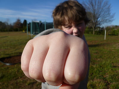 person wearing gray long-sleeved shirt shows right fist during daytime thumbnail