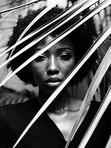 gray scale photo of woman in v-neck top behind tree leaf thumbnail