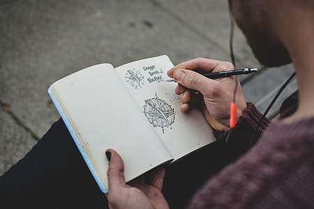person sits holding book and pen thumbnail