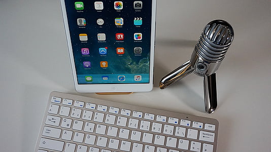 white iPad turned on beside condenser microphone and Apple Magic keyboard thumbnail
