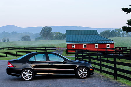 black sedan parked on concrete ground near red and black barn house thumbnail