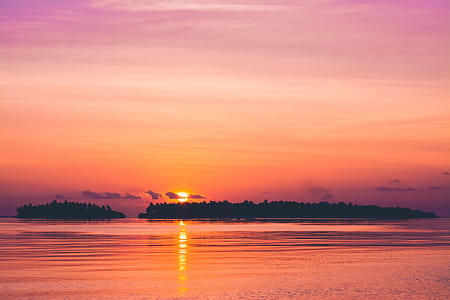 two island surrounding calm body of water during golden hour thumbnail
