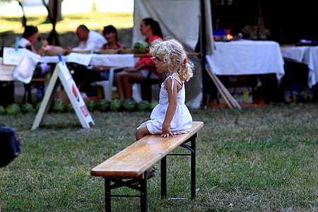 girl in white dress sitting on brown wooden bench thumbnail