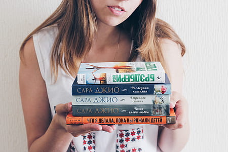 woman holding five assorted-title books thumbnail
