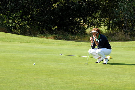 person squatting down holding golf club waiting for ball to fall in hole thumbnail
