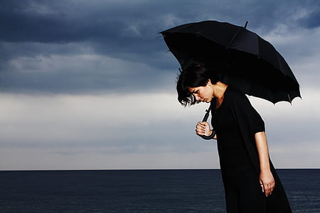 person in black holding a umbrella thumbnail