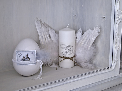 white candle beside feather on rack thumbnail