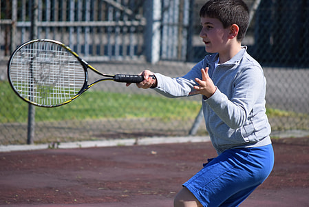 boy holding black and yellow Dunlop tennis racket thumbnail
