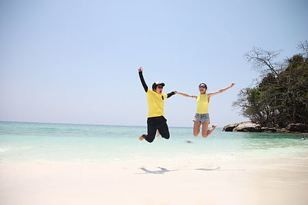 man and woman jumps on seashore thumbnail