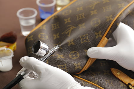 person spraying brown Louis Vuitton Monogram leather bag thumbnail
