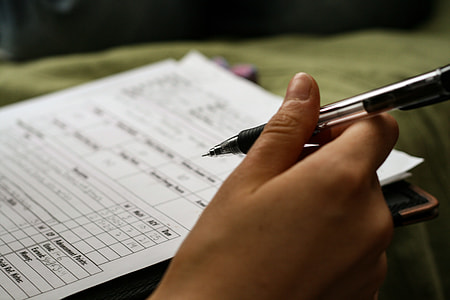 person holding ballpoint pen pointing on paper thumbnail