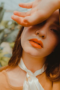 woman wearing brown top covering her eyes with hand thumbnail