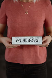 A young woman is holding a Girlboss Desk Sign thumbnail