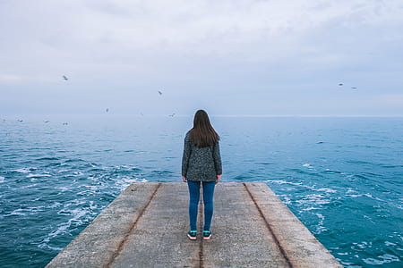 woman standing on wooden dock under clear blue sky during daytime thumbnail