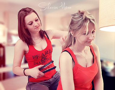 woman flat ironing another woman's hair thumbnail