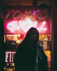 woman in black jacket standing in front of Tokyo Grill neon signage thumbnail
