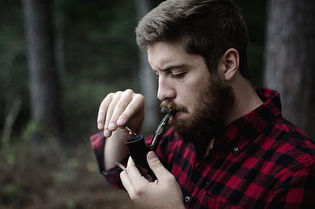 man in black and red gingham dress shirt holding smoking pipe thumbnail