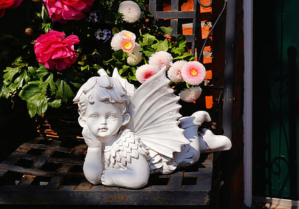 cherub ceramic figurine near white petaled flowers thumbnail