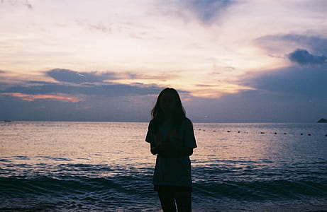 Silhouette of Woman Standing Near Large Body of Water thumbnail