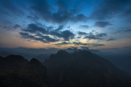silhouette photography of mountains under nimbus clouds thumbnail