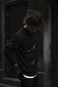 man wearing black sweater near gray concrete building thumbnail