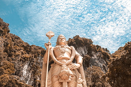 gold-colored Buddha statue with brown mountain in background under blue sky during daytime thumbnail