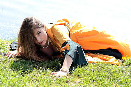 woman lying on green grass near body of water at daytime thumbnail