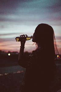 girl wearing black 3/4-sleeved top drinking black labeled plastic bottle thumbnail