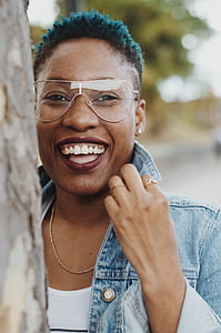 woman leaning on gray tree smiling thumbnail