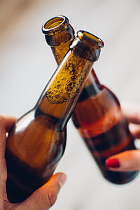 persons holding brown glass bottles thumbnail