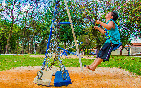 boy riding on playground swing thumbnail