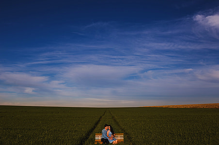 man and woman sitting on bench surrounded by grass thumbnail