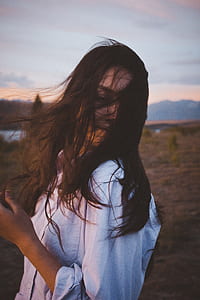 woman wearing white collared shirt with her hair covering her face outdoors thumbnail