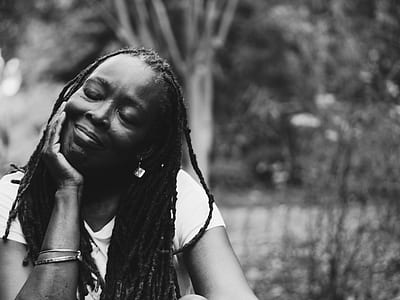 gray scale photography of woman sitting near tree thumbnail