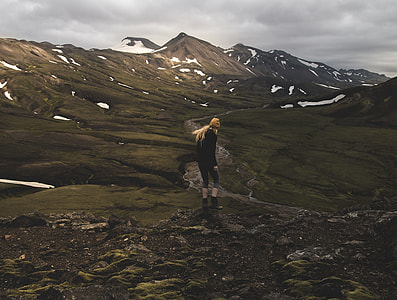 woman standing at top of mountain near mountain range covered with snow thumbnail