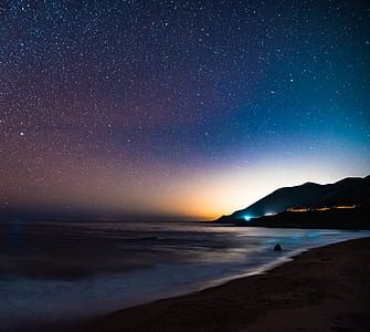 body of water beside of sandbank during nighttime thumbnail