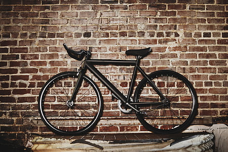 black road bike beside brown wall thumbnail