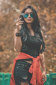 woman wearing pair of sunglasses smoking cigarette thumbnail