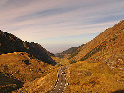 vehicle riding on gray concrete road between mountains thumbnail