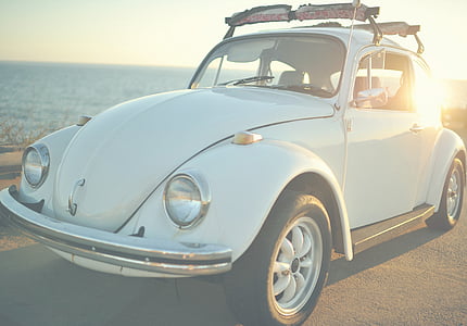white Volkswagen Beetle coupe park near body of water during daytime thumbnail