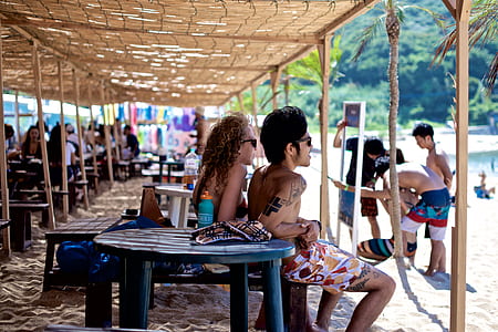 man and woman sitting on wooden bench by the beach thumbnail
